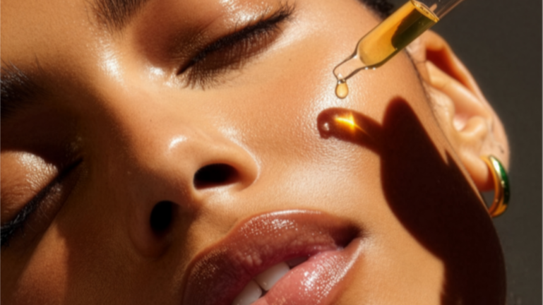 Close-up of a woman with a cosmetic dropper applying serum to her cheek.