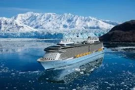 Large cruise ship sailing near icy mountains and glacier in a fjord