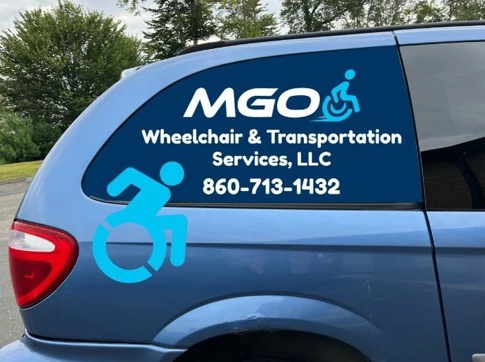 Blue vehicle with signage for MGO Wheelchair & Transportation Services, LLC, including a wheelchair symbol and contact number 860-713-1432.