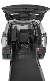 A rear view of an open wheelchair-accessible van with a lowered ramp, showing empty space and foldable seats inside