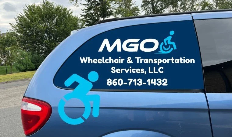 Blue vehicle with signage for MGO Wheelchair & Transportation Services, LLC, including a wheelchair icon, a person in a wheelchair icon, and contact number 860-713-1432.