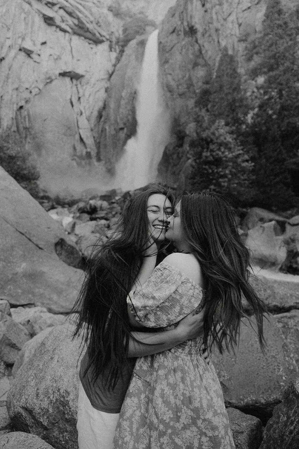 lgbtq couple shares a kiss at waterfall in Yosemite national park