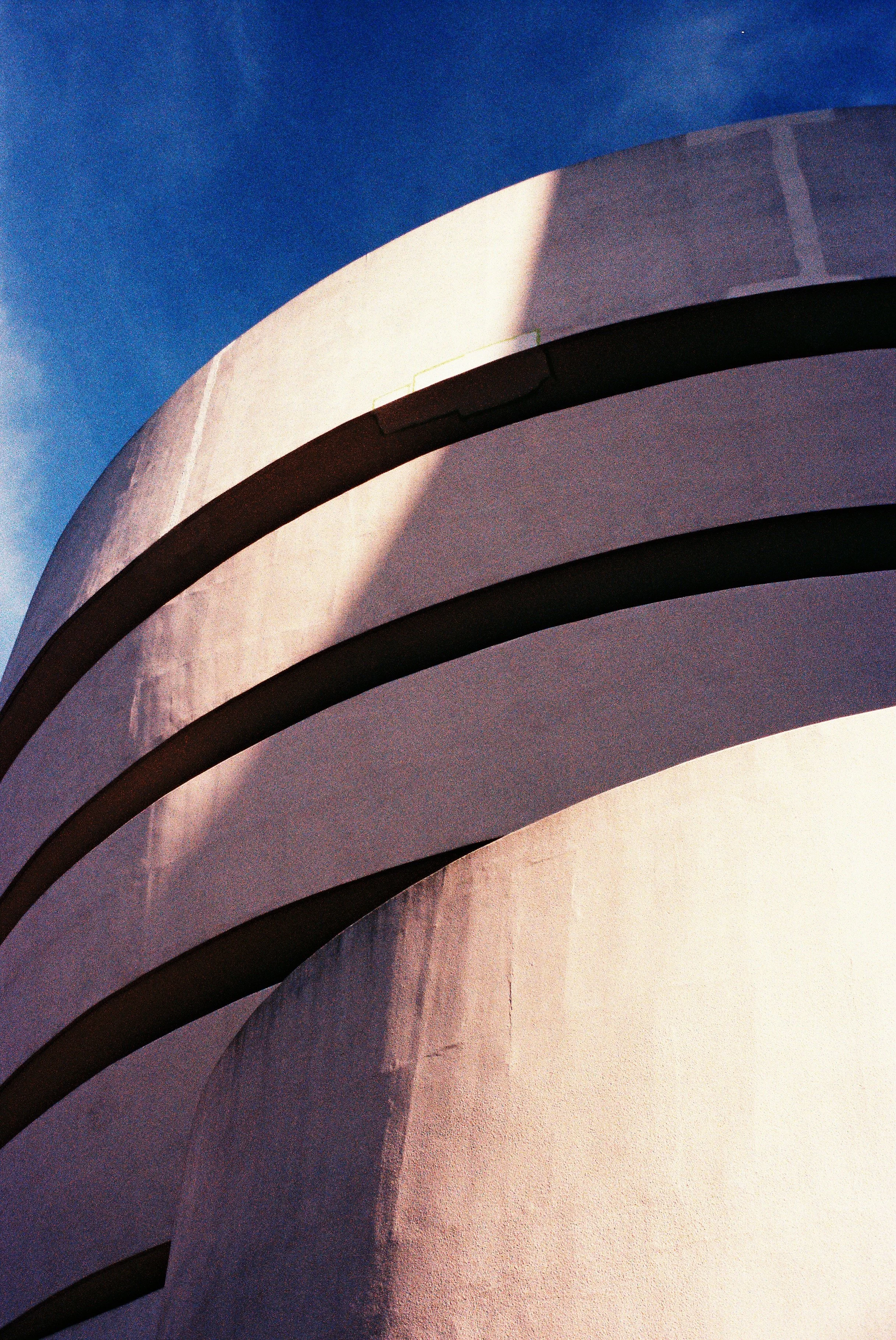Close-up of a modern building's curved architectural design against a blue sky.