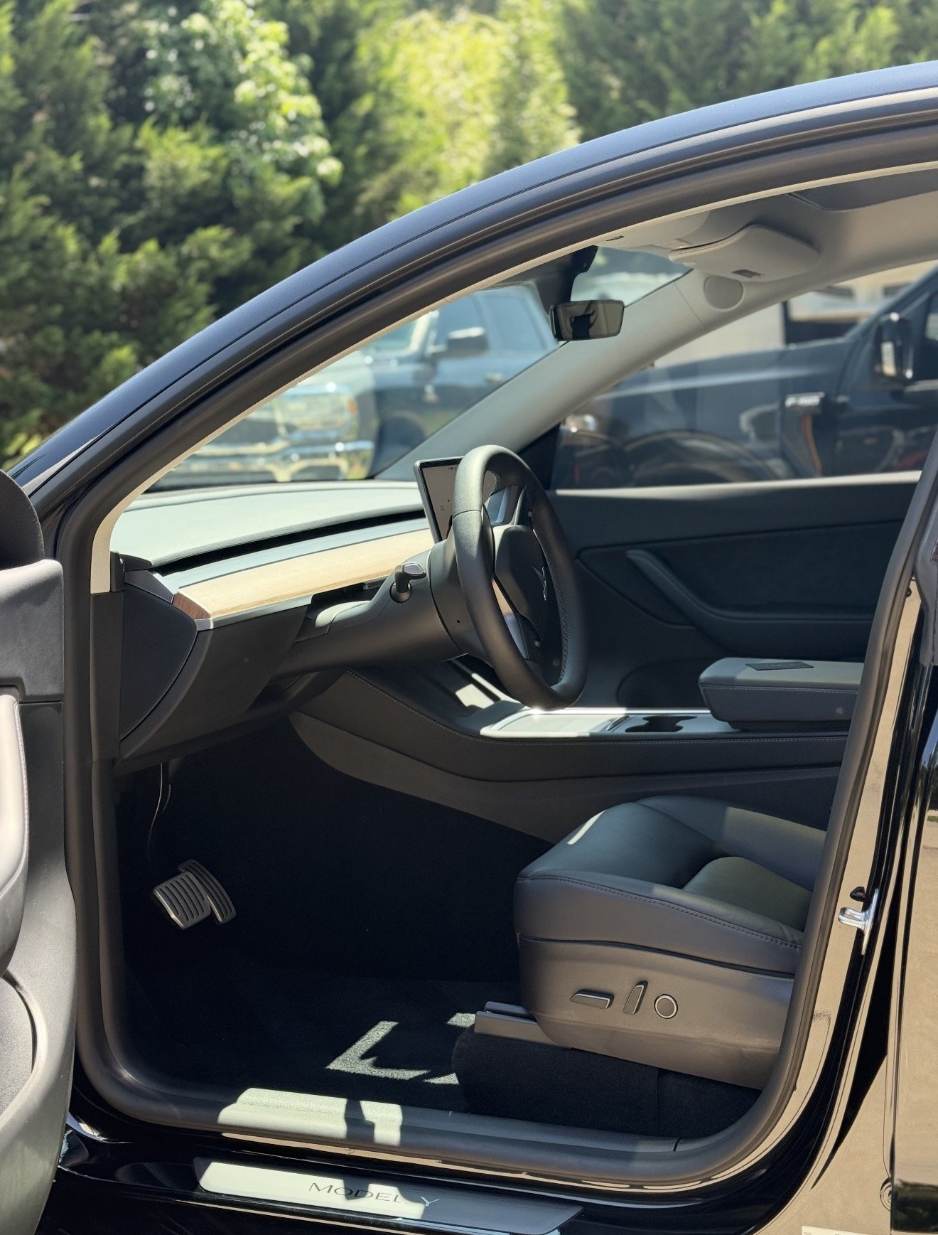 Interior of a modern electric vehicle with a minimalist dashboard, a digital display, and black leather seats.