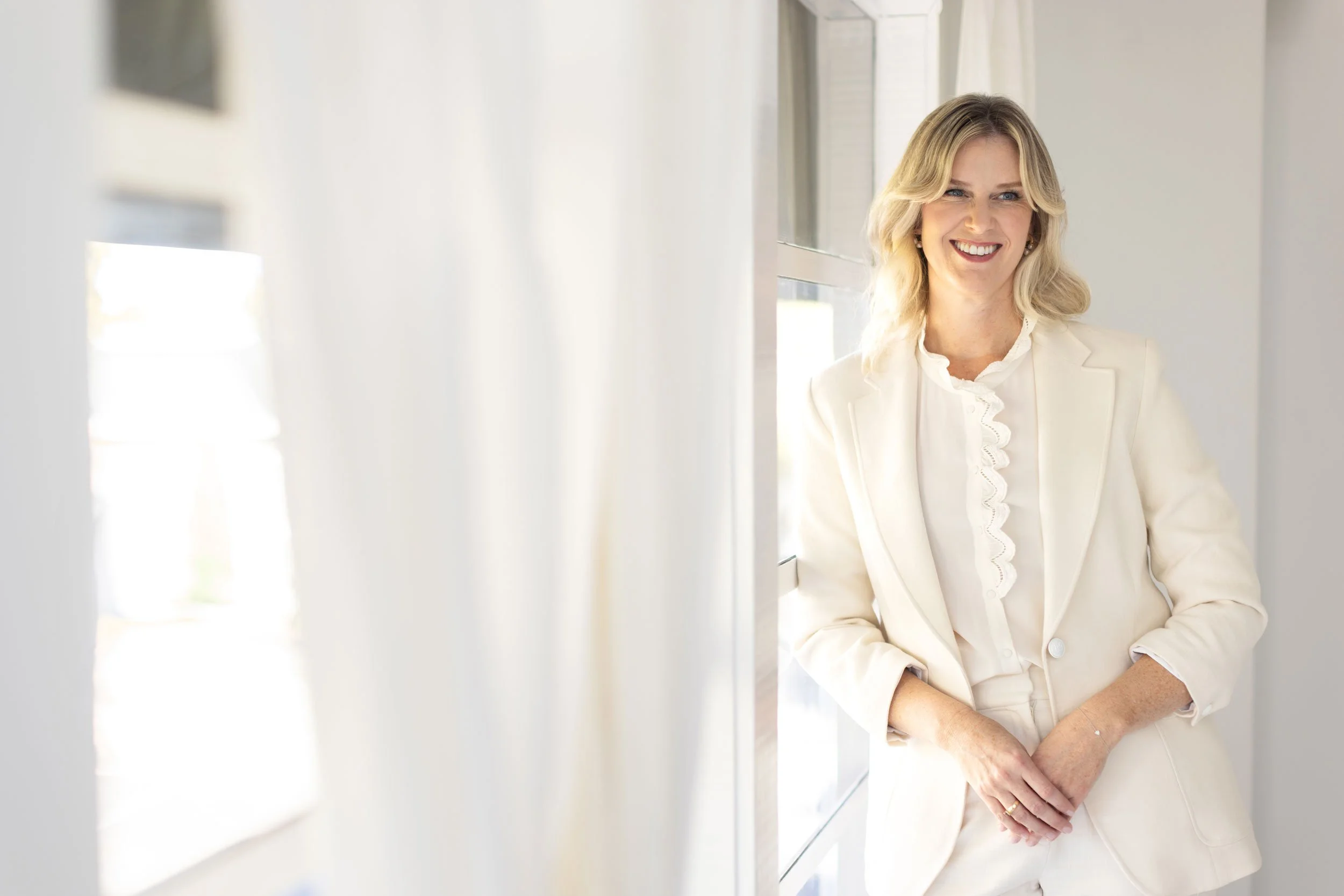 Stephanie Rooney leaning against a window in natural light.