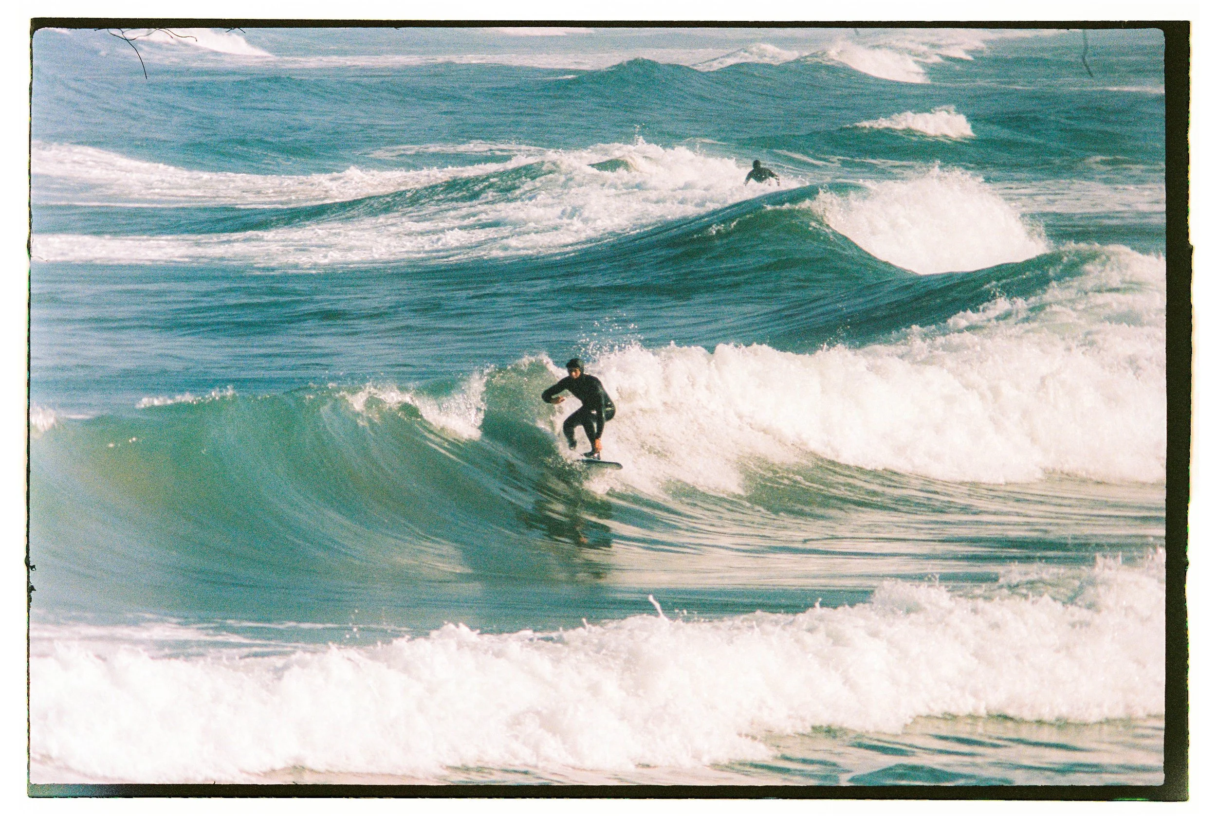 Surfer riding a wave in the ocean with multiple waves in the background.