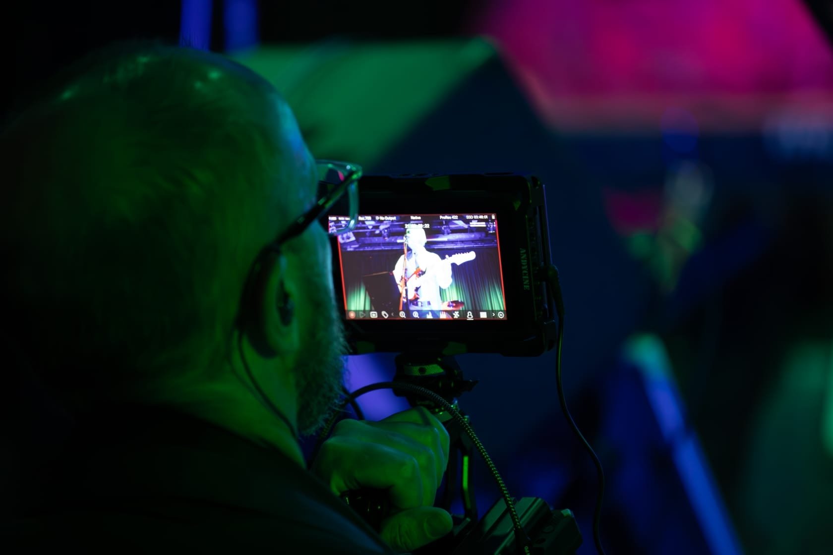 A person using a camera to film a musician performing on stage with a guitar.