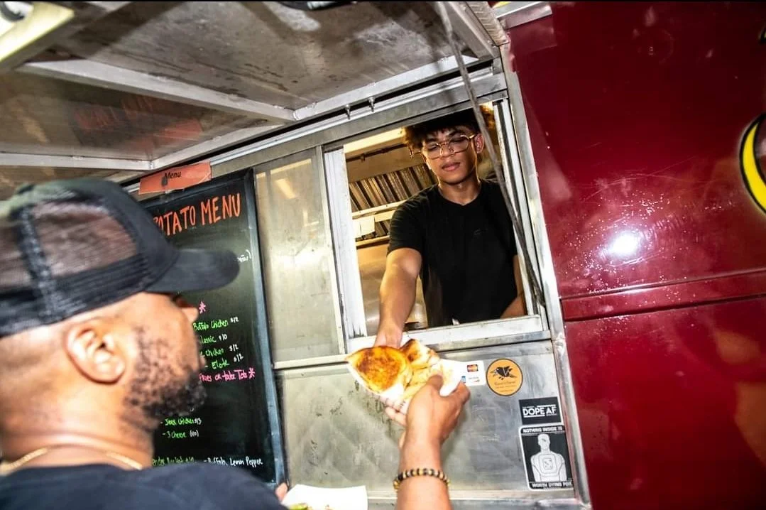 A person receiving food from a food truck worker through the window.