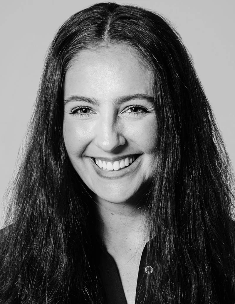 Black and white portrait of a smiling woman with long, dark hair wearing a dark shirt.