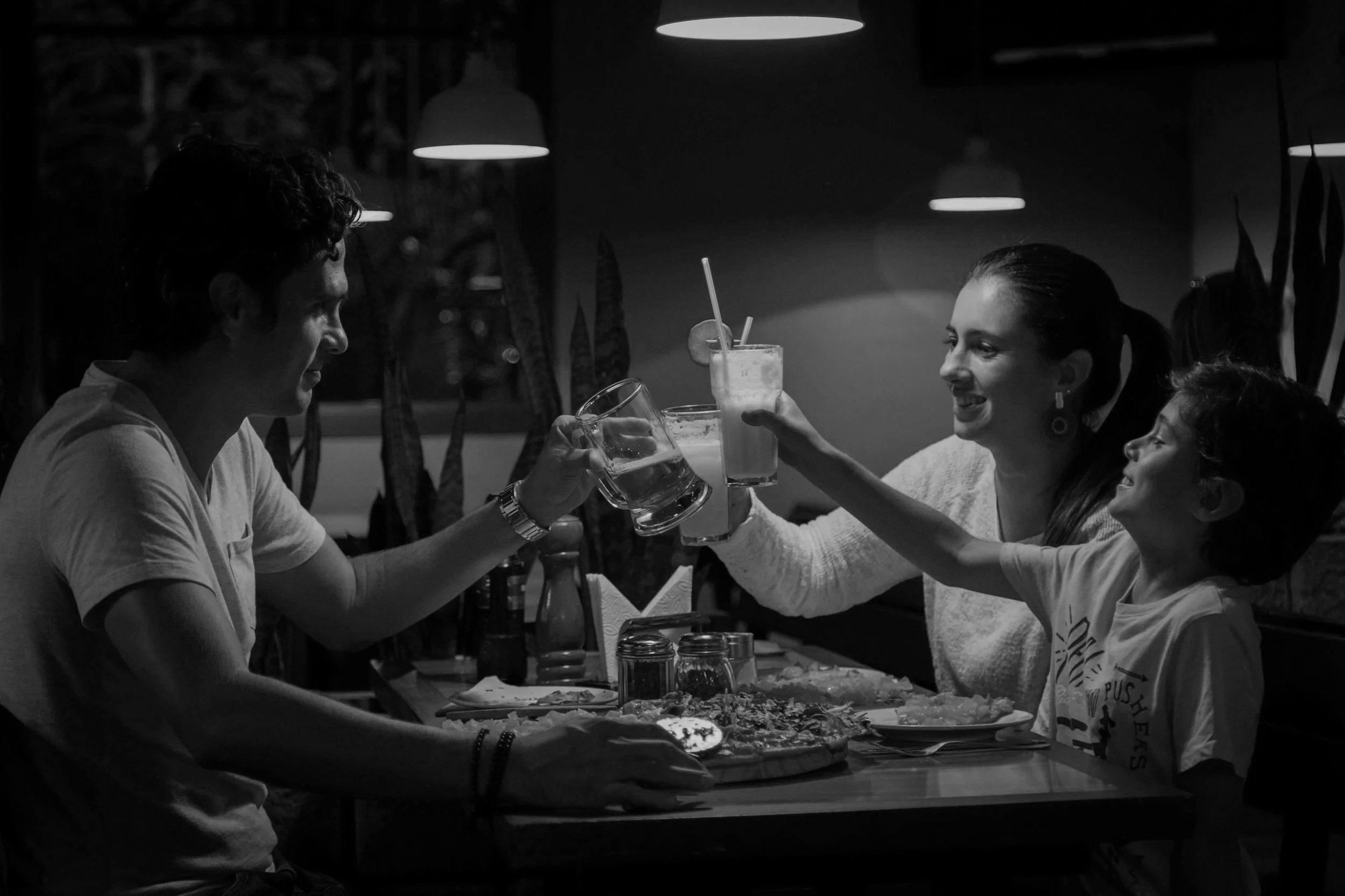 A group of friends at a restaurant, raising their glasses in a toast, with smiles and laughter, in a cozy dining setting.