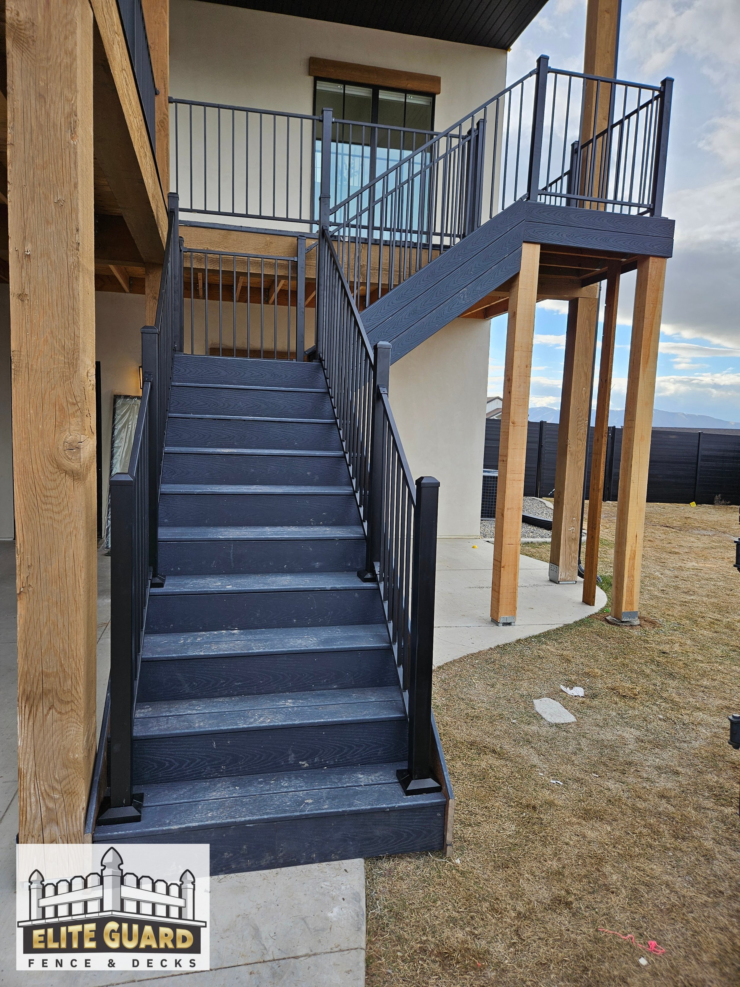 Black metal staircase leading to an upper balcony on a modern house with wooden and metal railings, with a cloudy sky in the background in Salem, Utah.