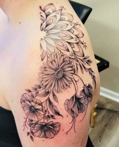 Tattoo of flowers and leaves on upper arm and shoulder.