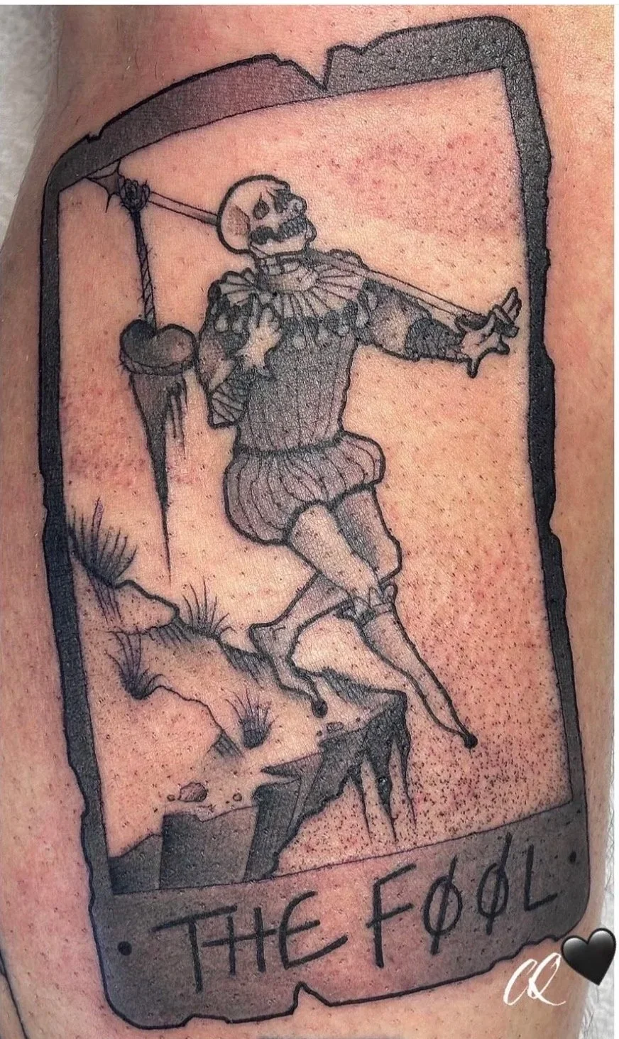 Tattoo of a skeleton dressed as a jester, hanging from a noose, with the banner reading 'THE FOOL'
