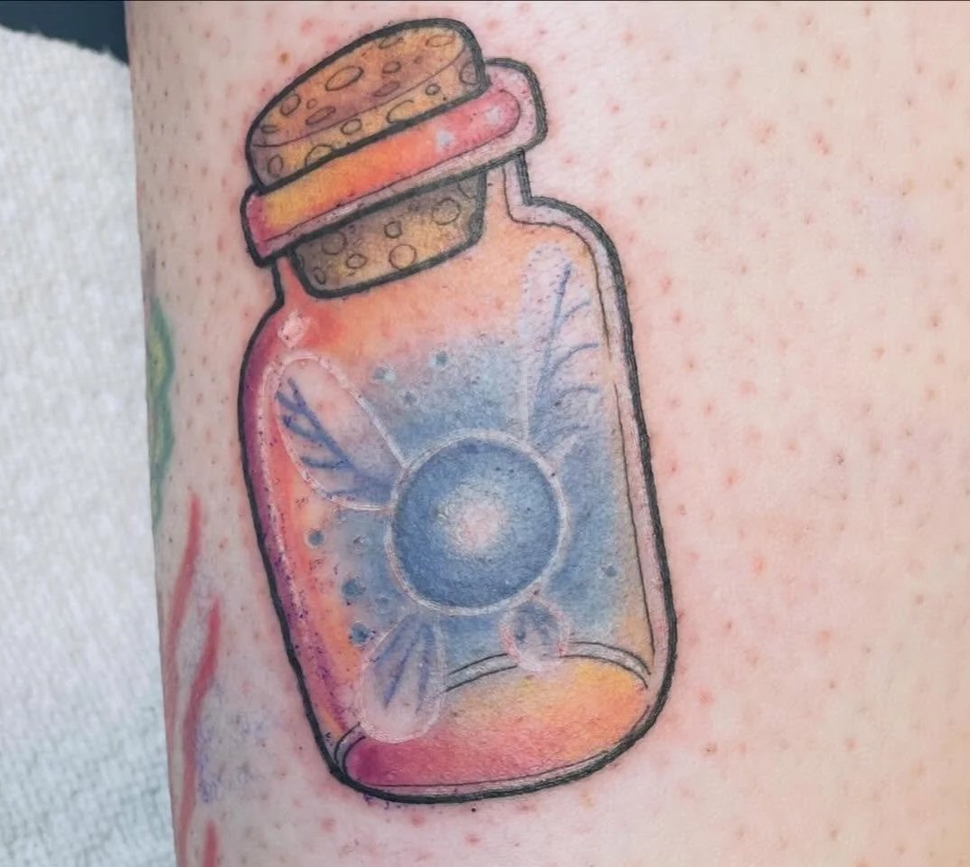 Tattoo of a medicine bottle with a blue sun design and a red and black cap.