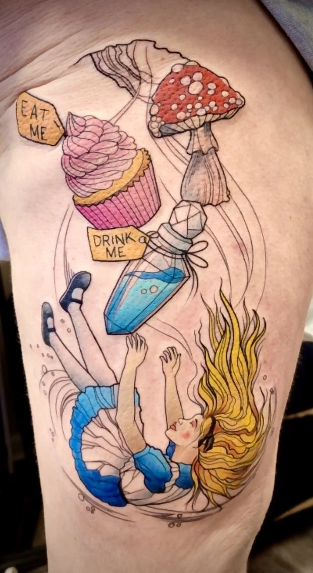 Colorful tattoo of a girl in a blue dress swimming underwater, surrounded by floating desserts including a cupcake with pink frosting, a mushroom-shaped cake, and a perfume bottle with tags reading "Eat Me" and "Drink Me."