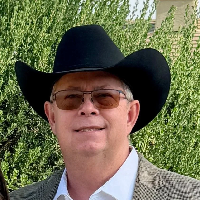 Russell Federico standing outside in a cowboy hat in front of greenery