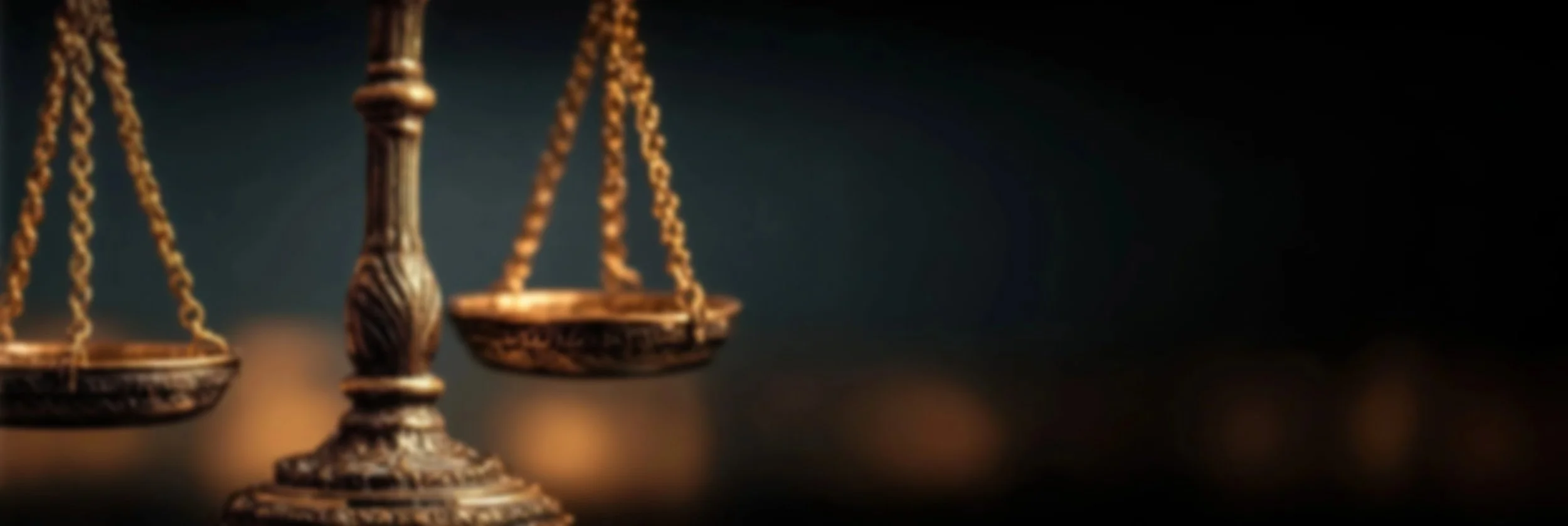 Close-up of a set of brass scales of justice against a dark background.
