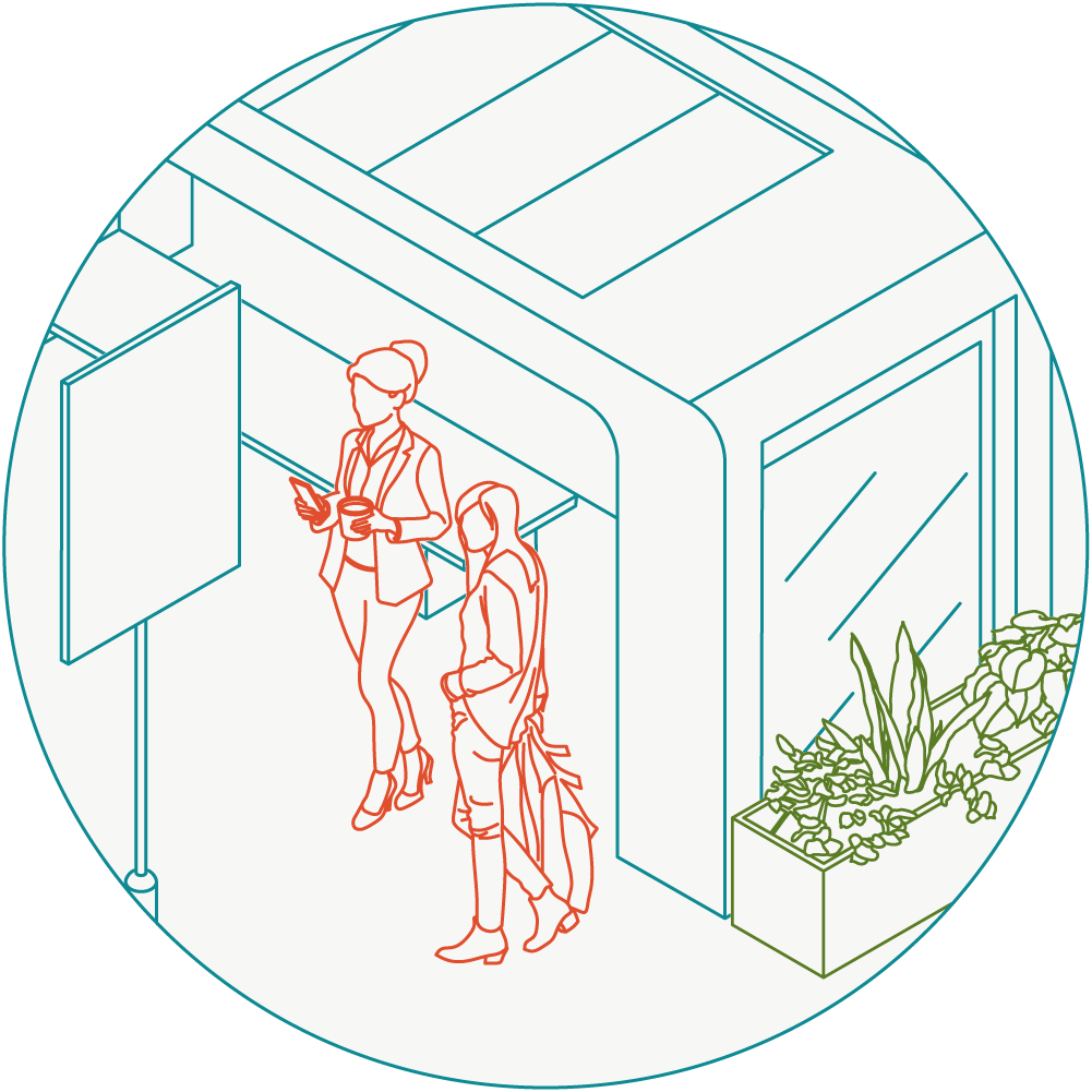 Two women waiting at a covered bus station, one is looking at a phone, the other is holding a coffee cup.