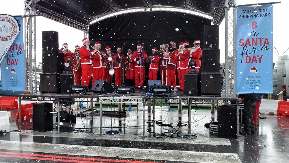 Band members dressed as Santa playing Christmas carols on stage