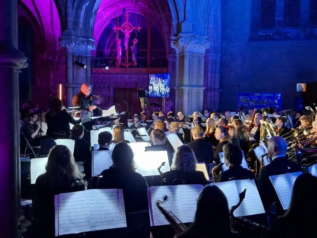 Band performing in a church illuminated by purple and blue lighting
