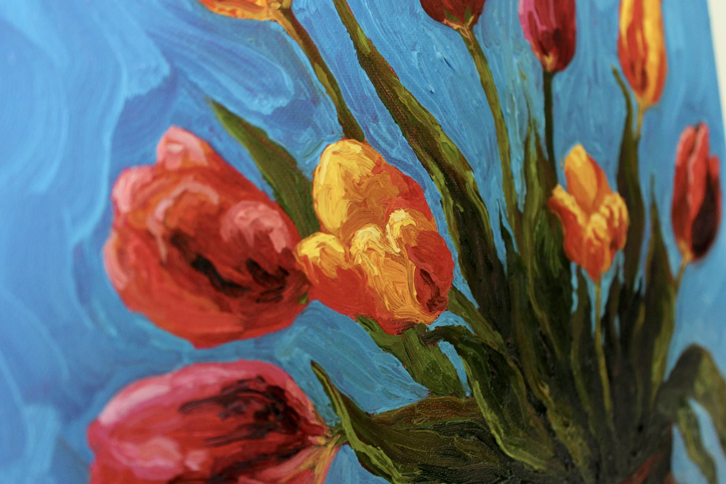 Detail view, focuses on the colorful red, pink, yellow, and oranges tulips.