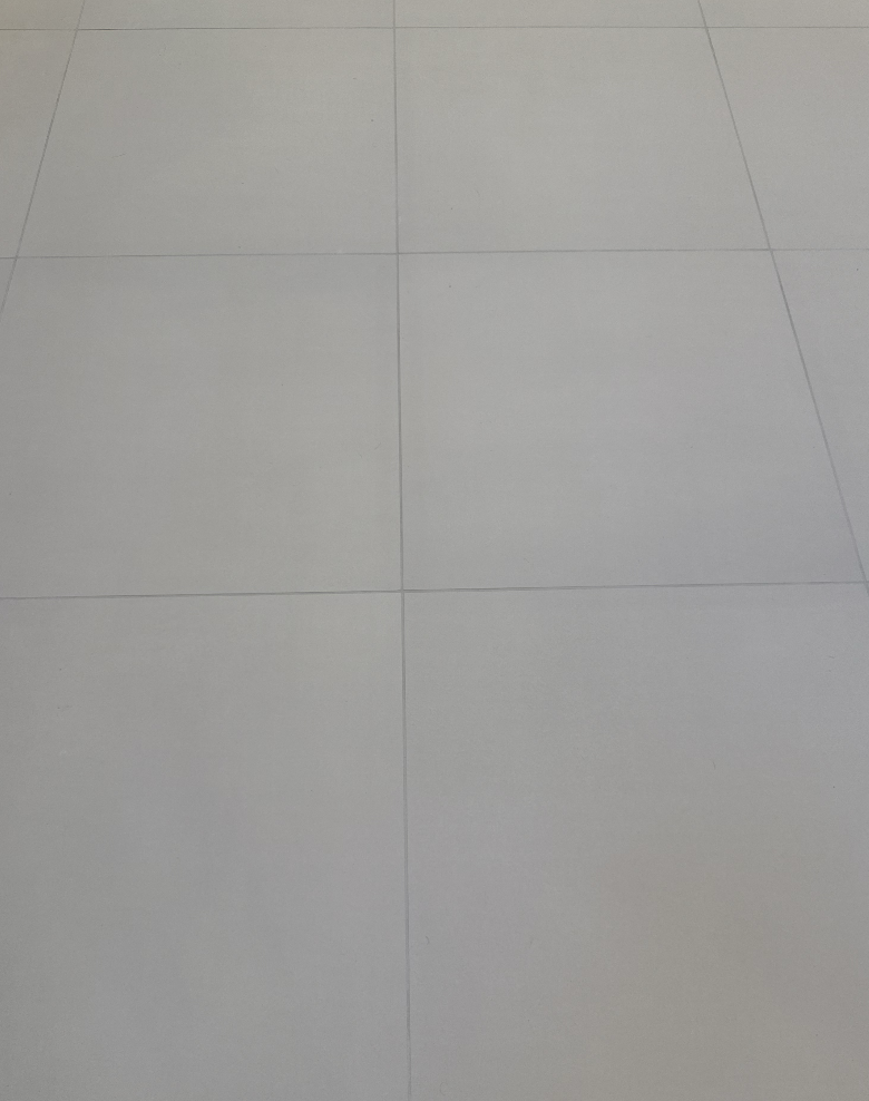 Close-up of white tiled floor with visible grout lines.