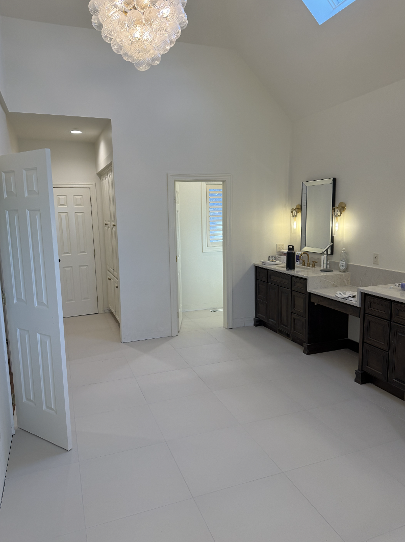 Luxurious bathroom with a dark wood vanity, marble countertop, mirror, and modern light fixtures, with a chandelier hanging from the ceiling.