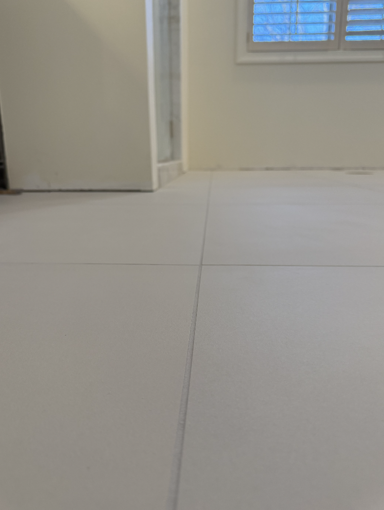 Interior view of a room with tiled floor, partially open door, and window with closed blinds.