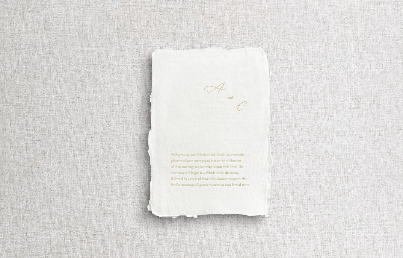 White main invitation on handmade paper with mix typography including calligraphy using gold foil letter press on neutral gray background.