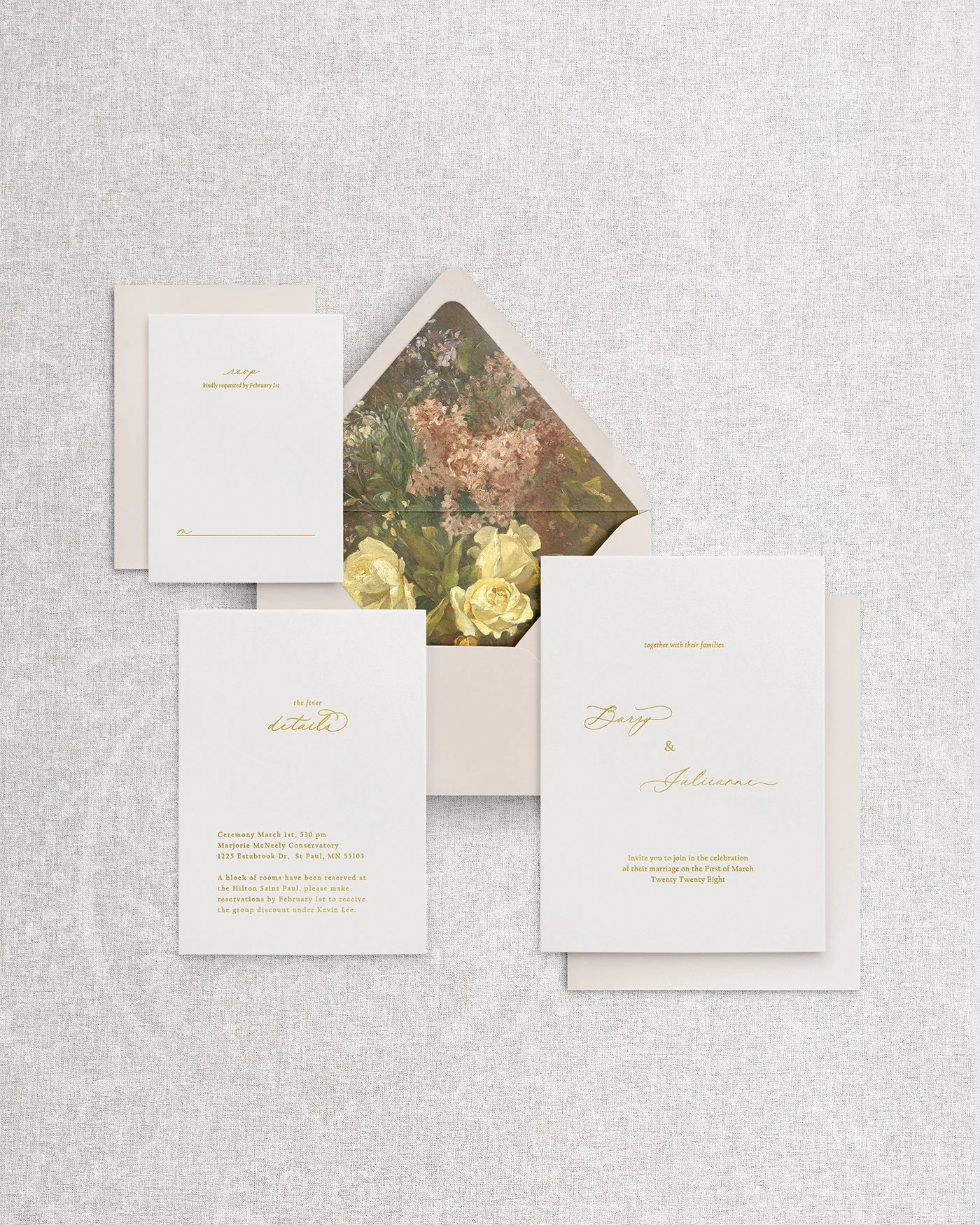 Flatlay of an elegant, simple wedding invitation suite featuring gold foil calligraphy on premium cardstock, paired with an open envelope showcasing a romantic floral liner.