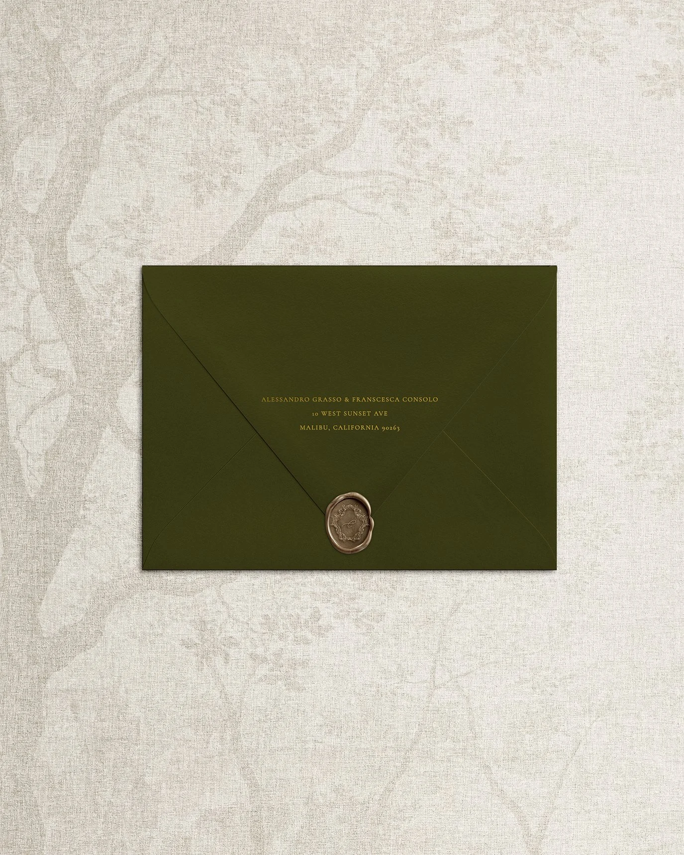 Deep green envelope with gold foil letterpress return address and vintage wax seal.