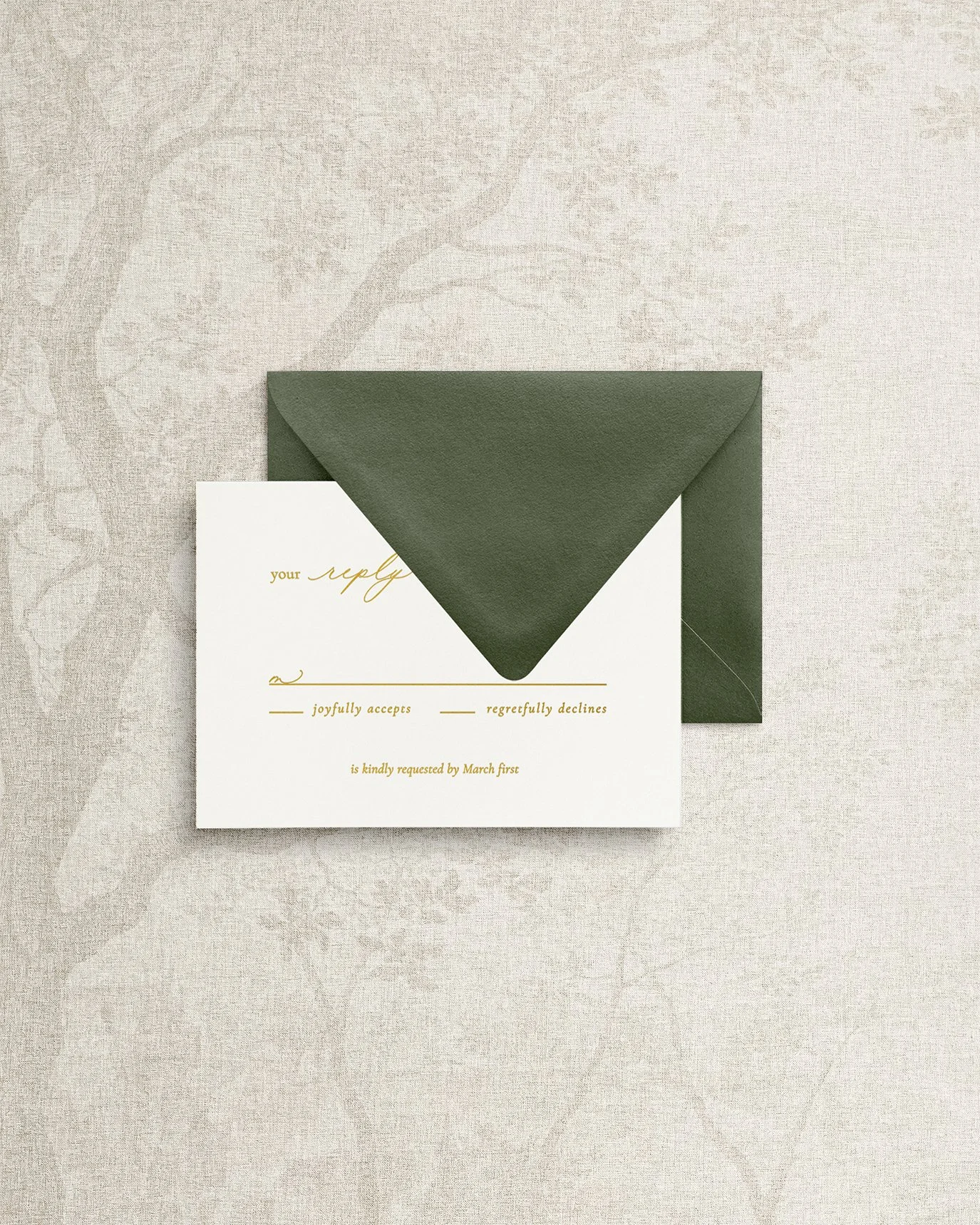 Elegant and simple wedding invitation RSVP card featuring gold foil calligraphy, paired with a dark green envelope.