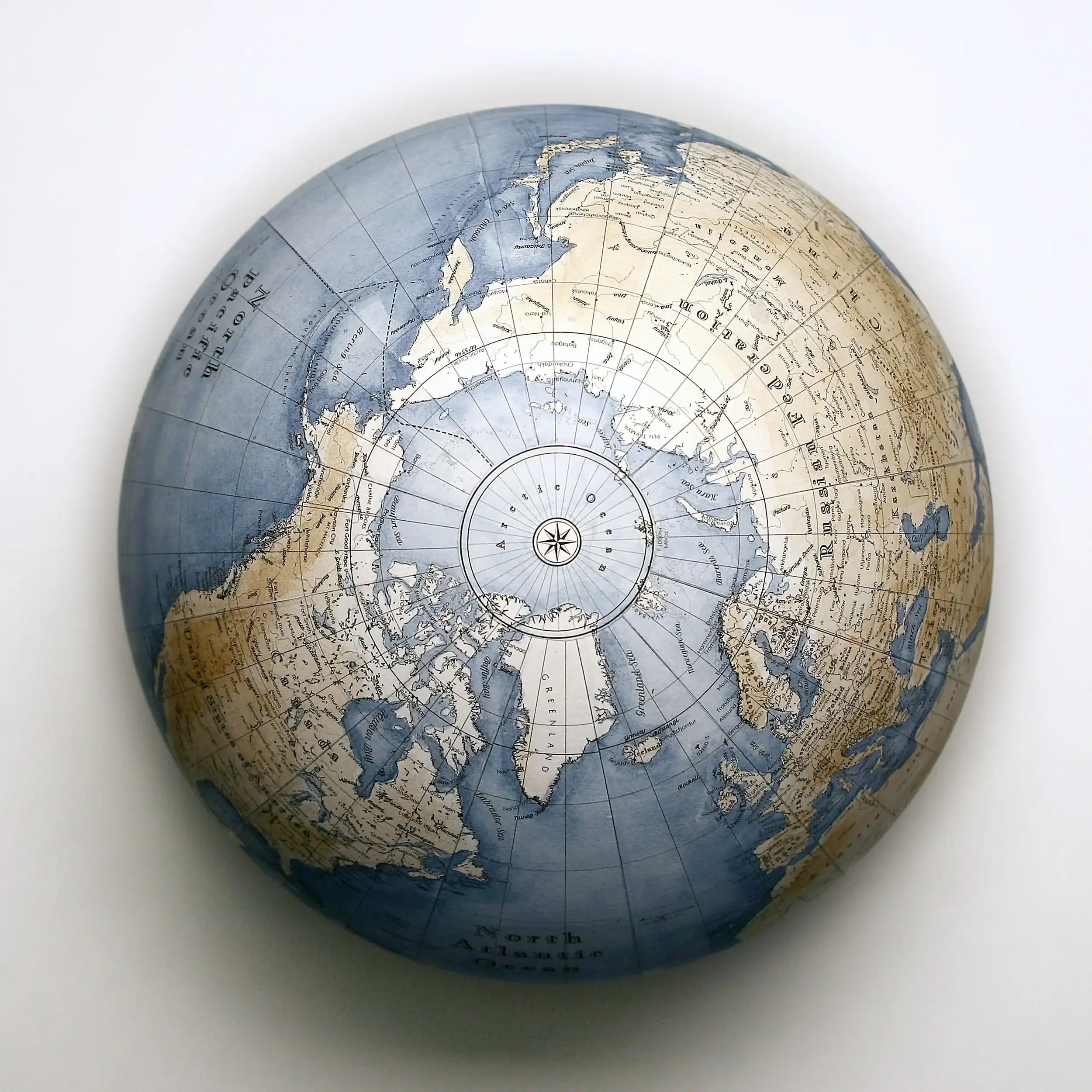 A globe map with Arctic and surrounding regions, showing oceans and continents in muted tones, placed on a white surface.