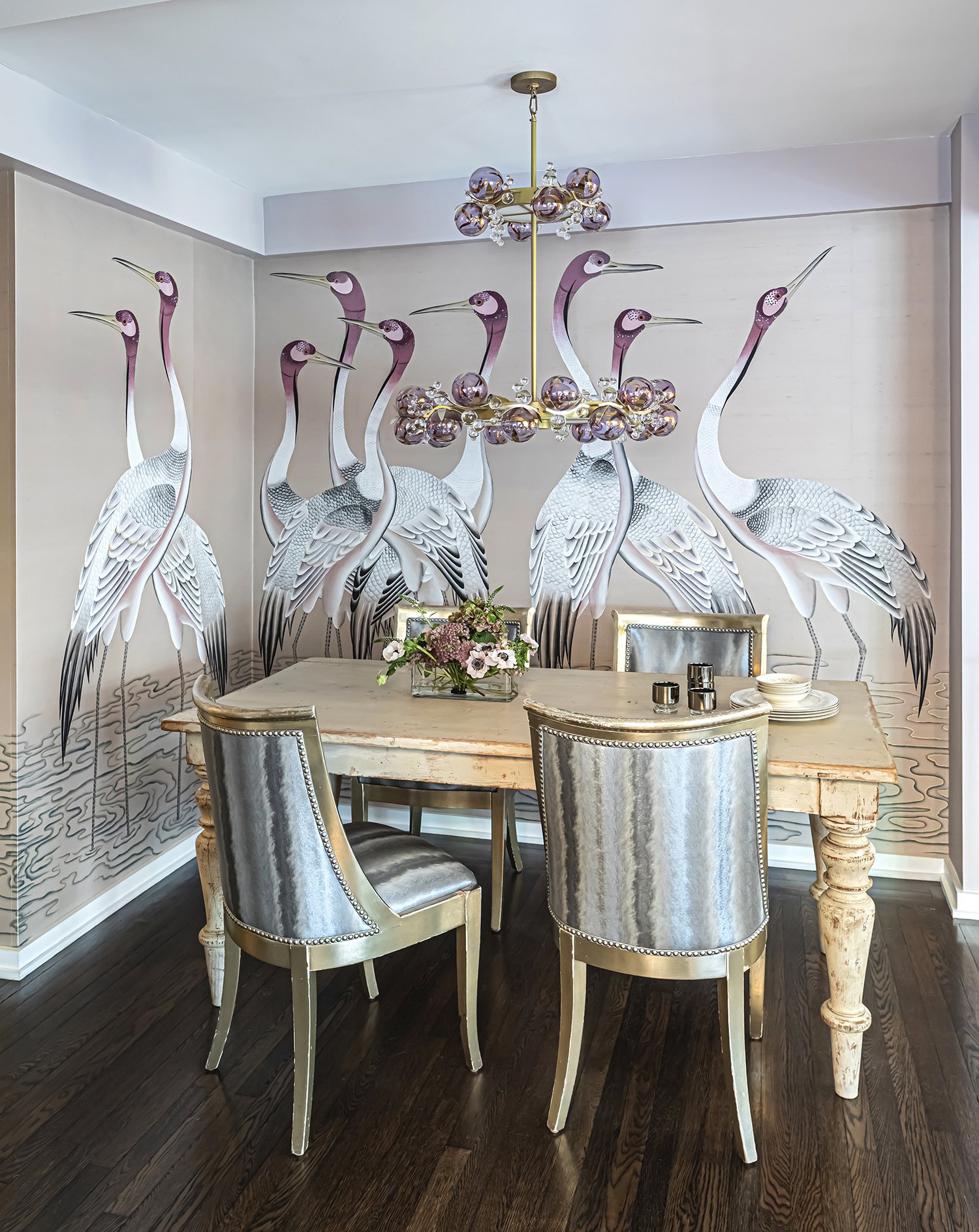 Dining room featuring a murals of cranes on the wall, with elegant chairs and a chandelier.