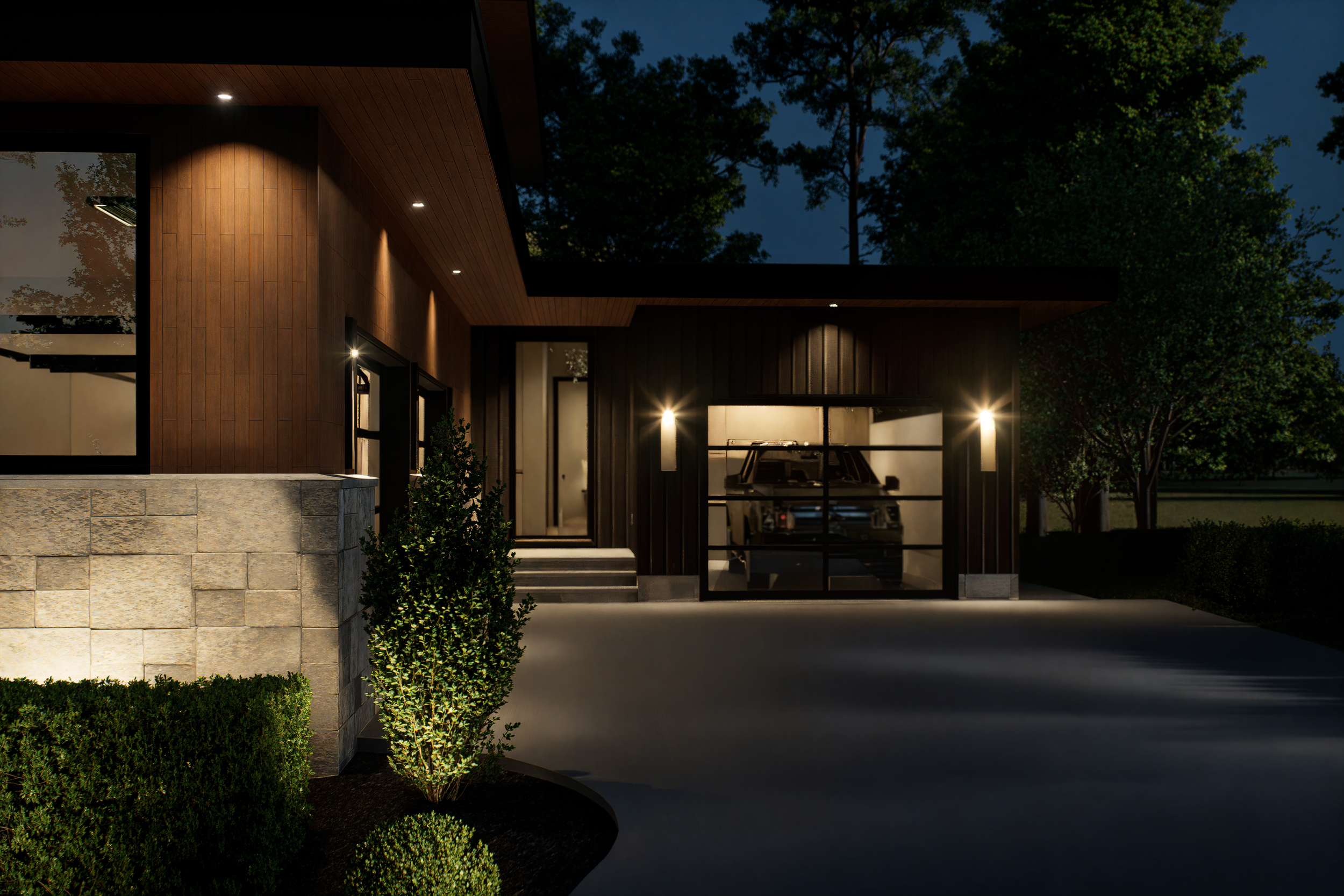 Nighttime view of a modern house with a garage door showing a parked vehicle inside, illuminated exterior lights, surrounded by trees and landscaping.
