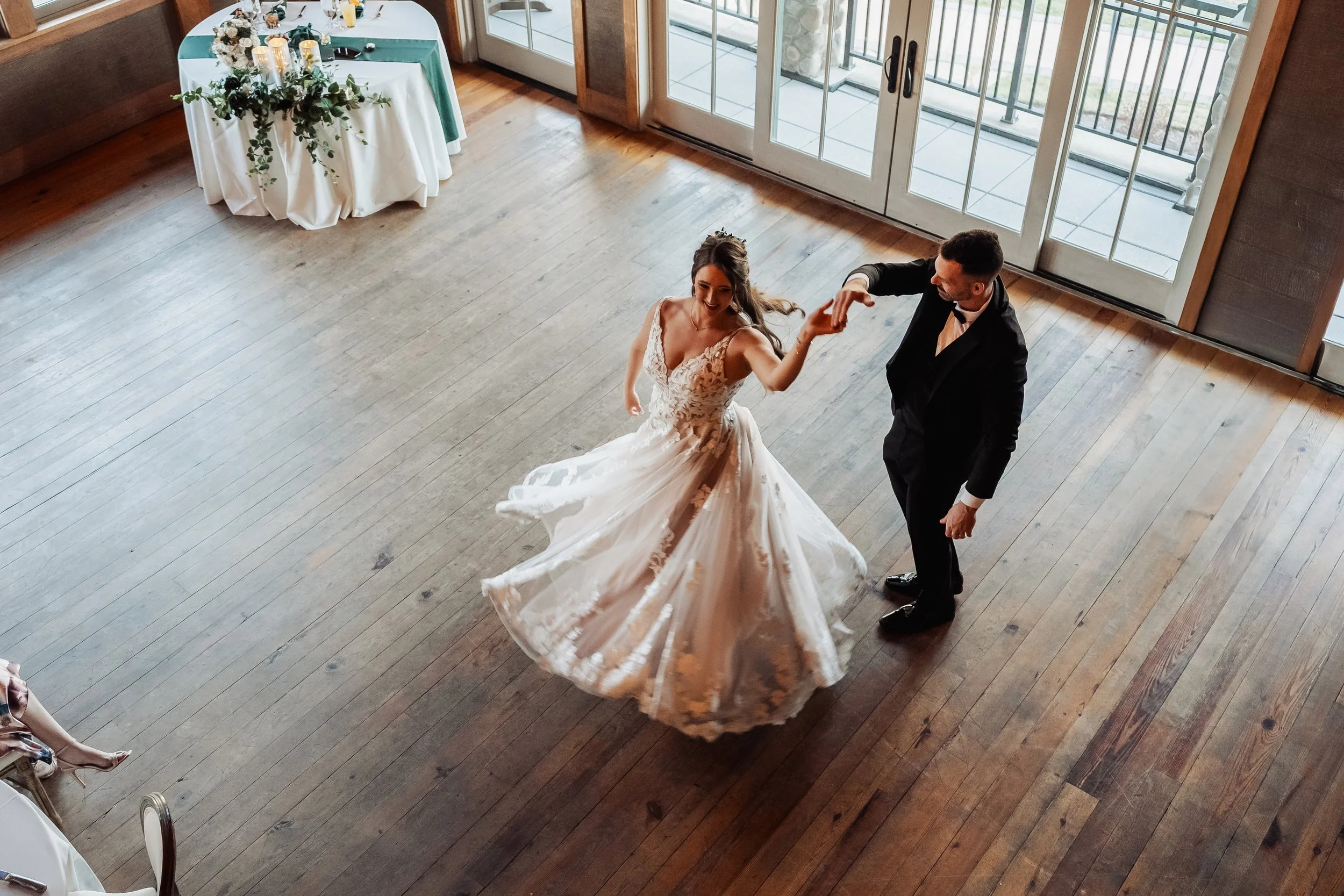 A groom spins his bride, her lacy skirt twirling around her as she moves.
