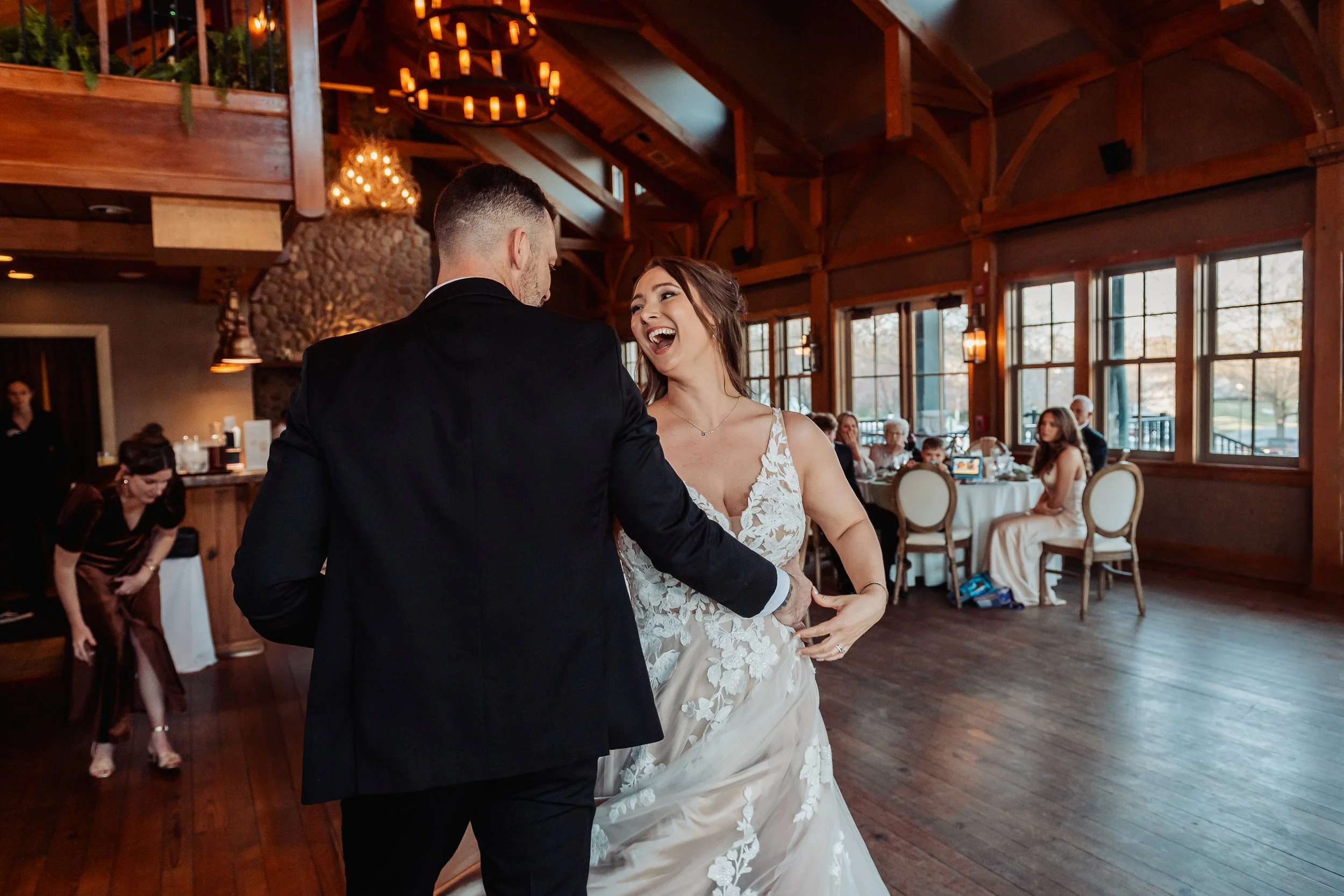 A bride smiles and laughs while dancing with her groom on their wedding day. Photo taken by Green Feather Photography