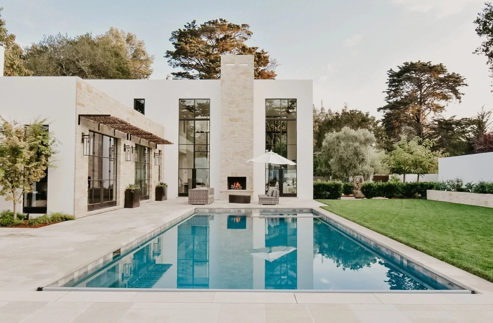 Modern house with a backyard pool, outdoor seating, and landscaped greenery.