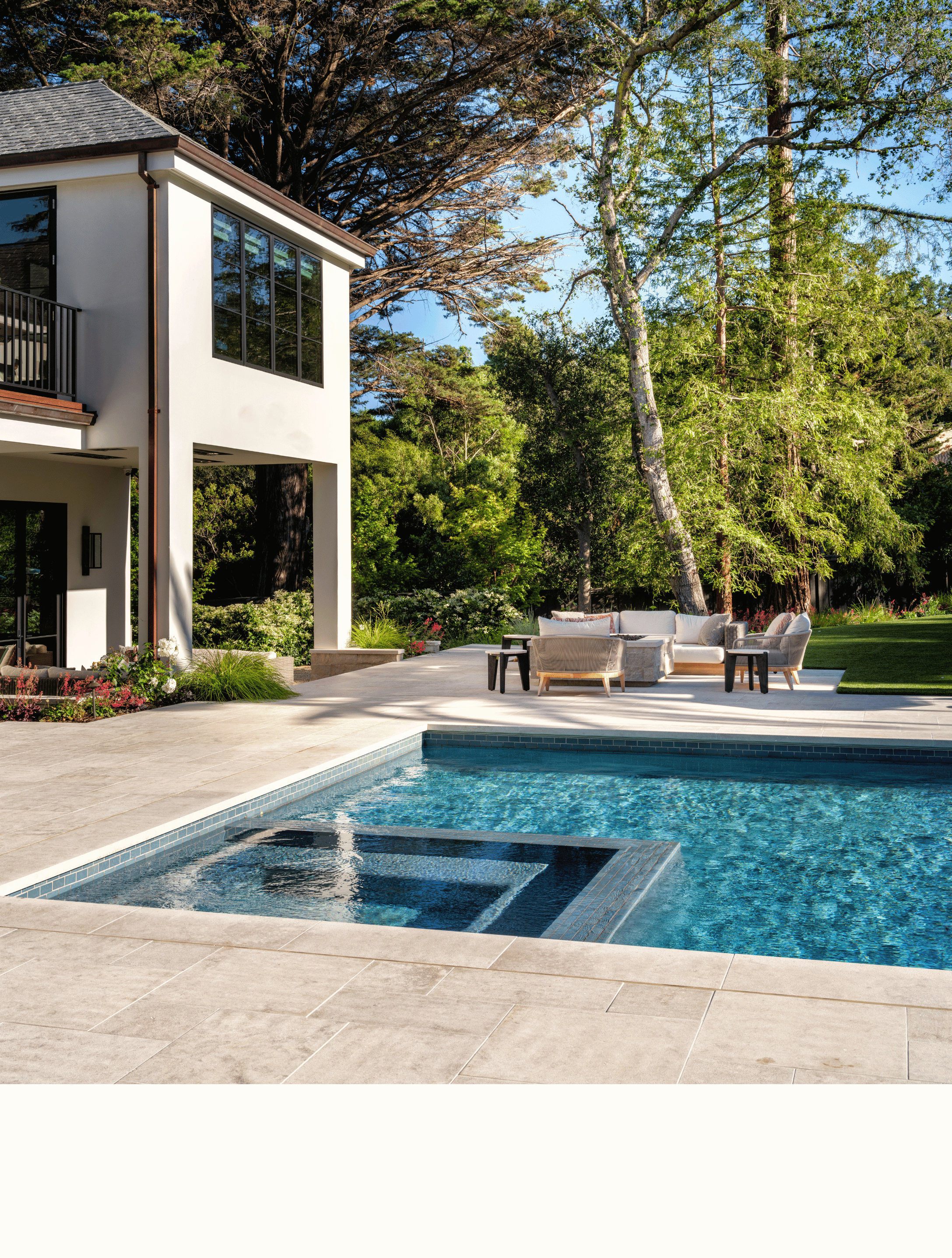 Backyard with swimming pool, outdoor seating area, and modern house surrounded by trees and greenery