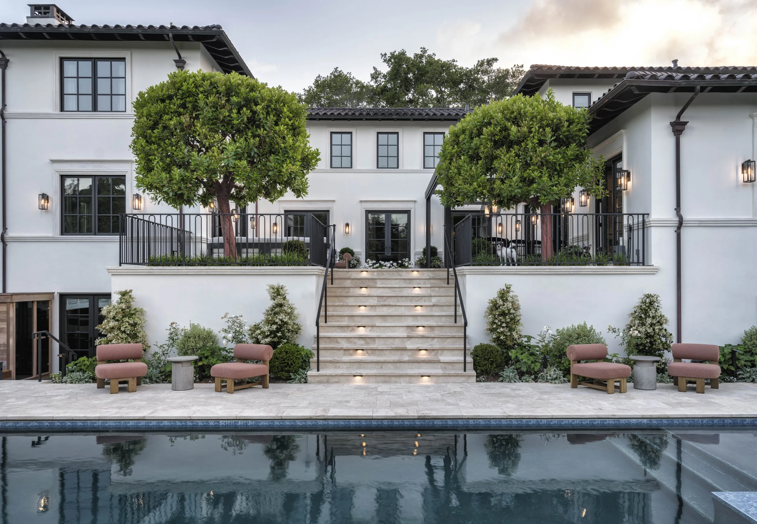 Luxury house with outdoor pool, stairs, lush greenery, outdoor seating, and modern lighting.