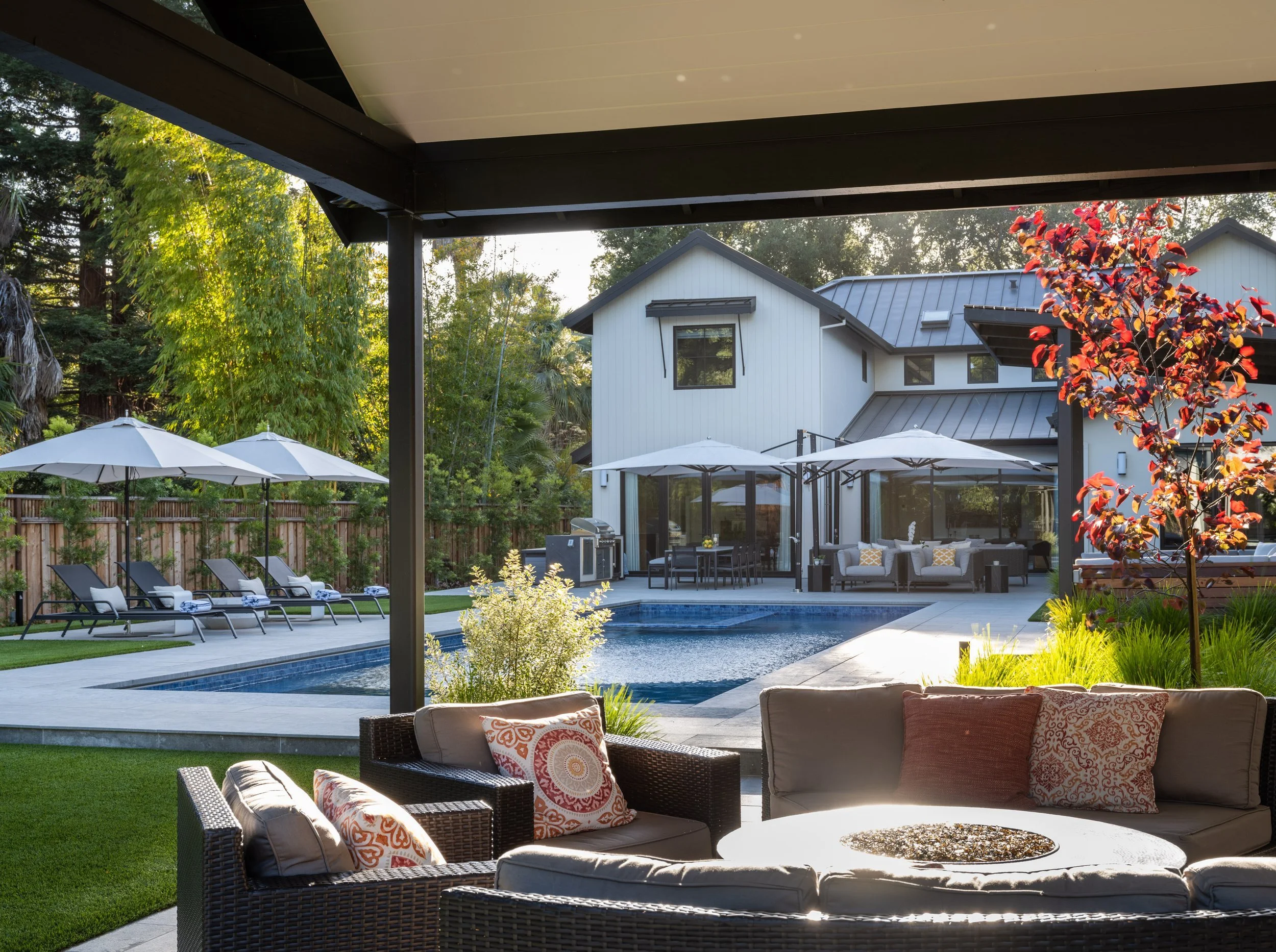 Backyard with swimming pool, lounge chairs, umbrellas, exterior patio furniture, and landscaped yard