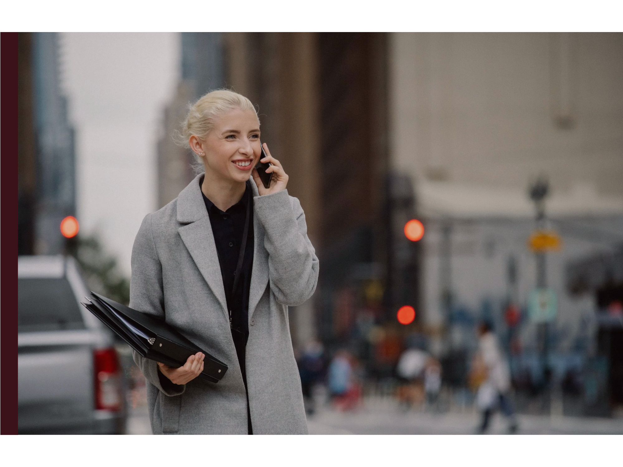 A woman walks on a busy street on the phone with a file