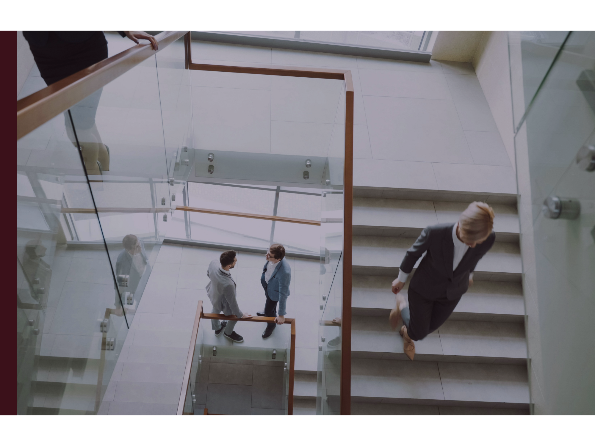 A busy office stairwell shows some colleagues in conversation and some heading to their next meeting