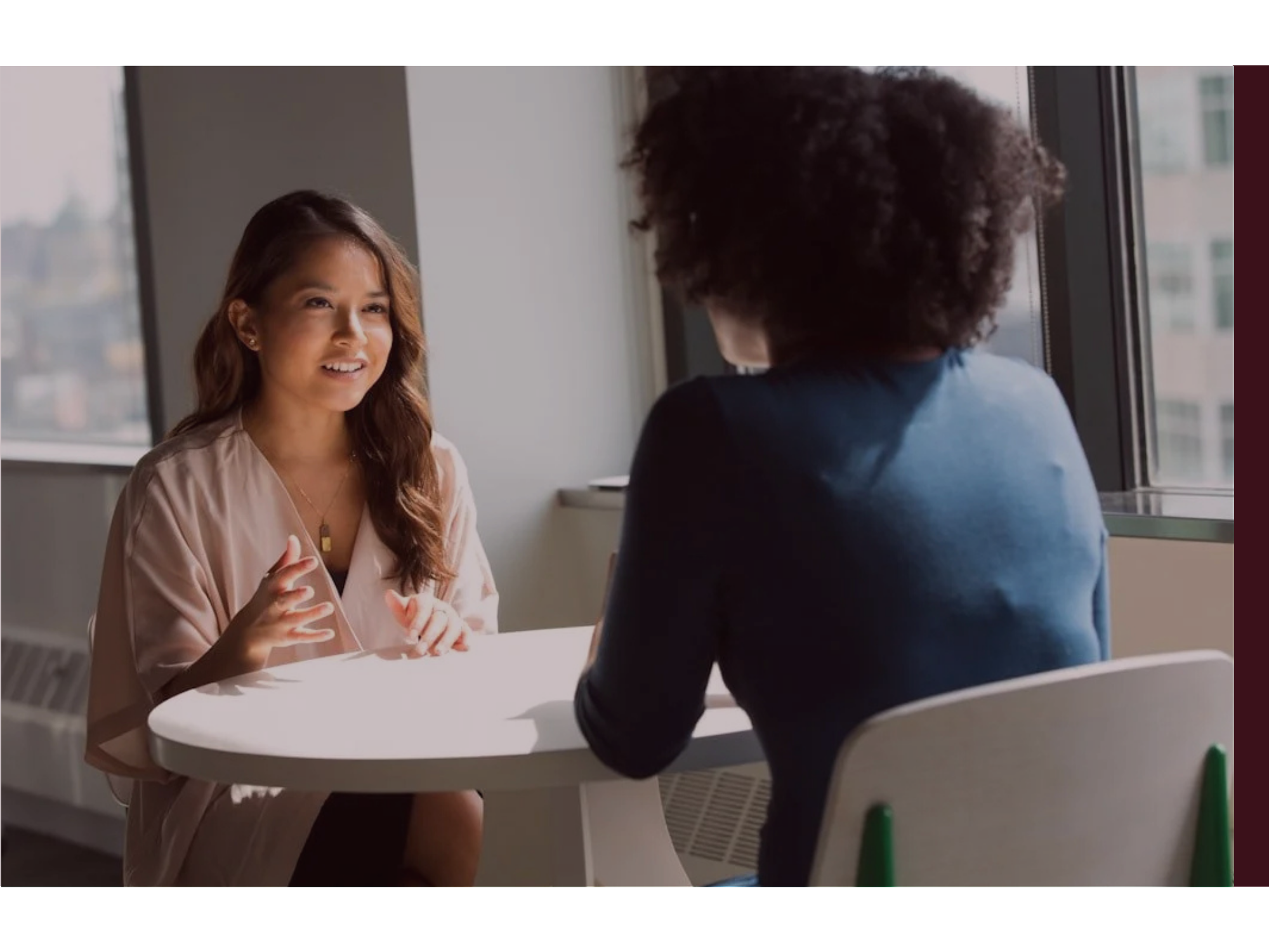 Two women sit at a table in discussion