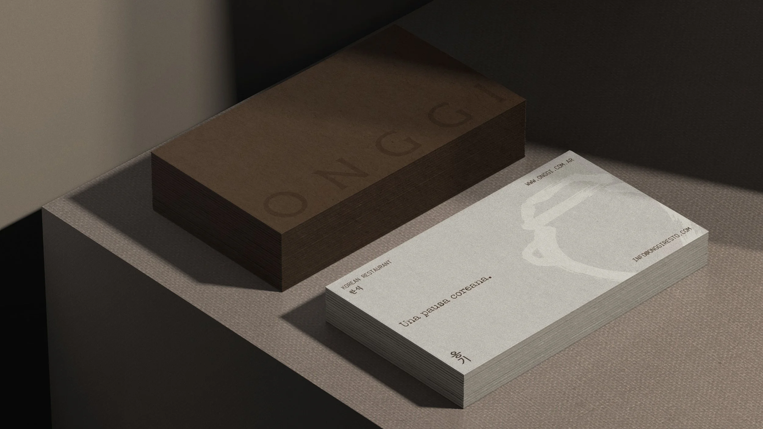 Tarjetas de visita apiladas en una mesa, una con diseño minimalista y otra con texto que dice 'Una pausa coreana' y 'Korean Restaurant'.