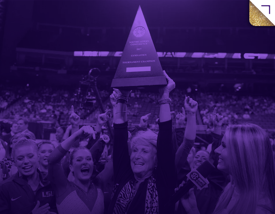Women celebrating on a gymnastics arena podium holding a tournament championship trophy, with purple overlay.