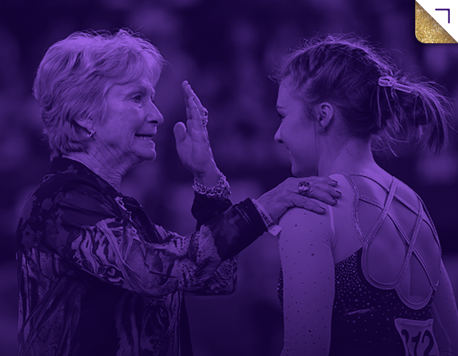 A woman and young female athlete engaging in a high-five or celebration, outdoors, both smiling.