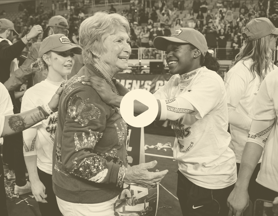 Woman and young female athlete smiling and embracing at a sports event.