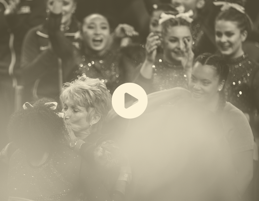 A woman and a girl share a hug, with a group of cheerleaders in the background displaying excitement and joy.