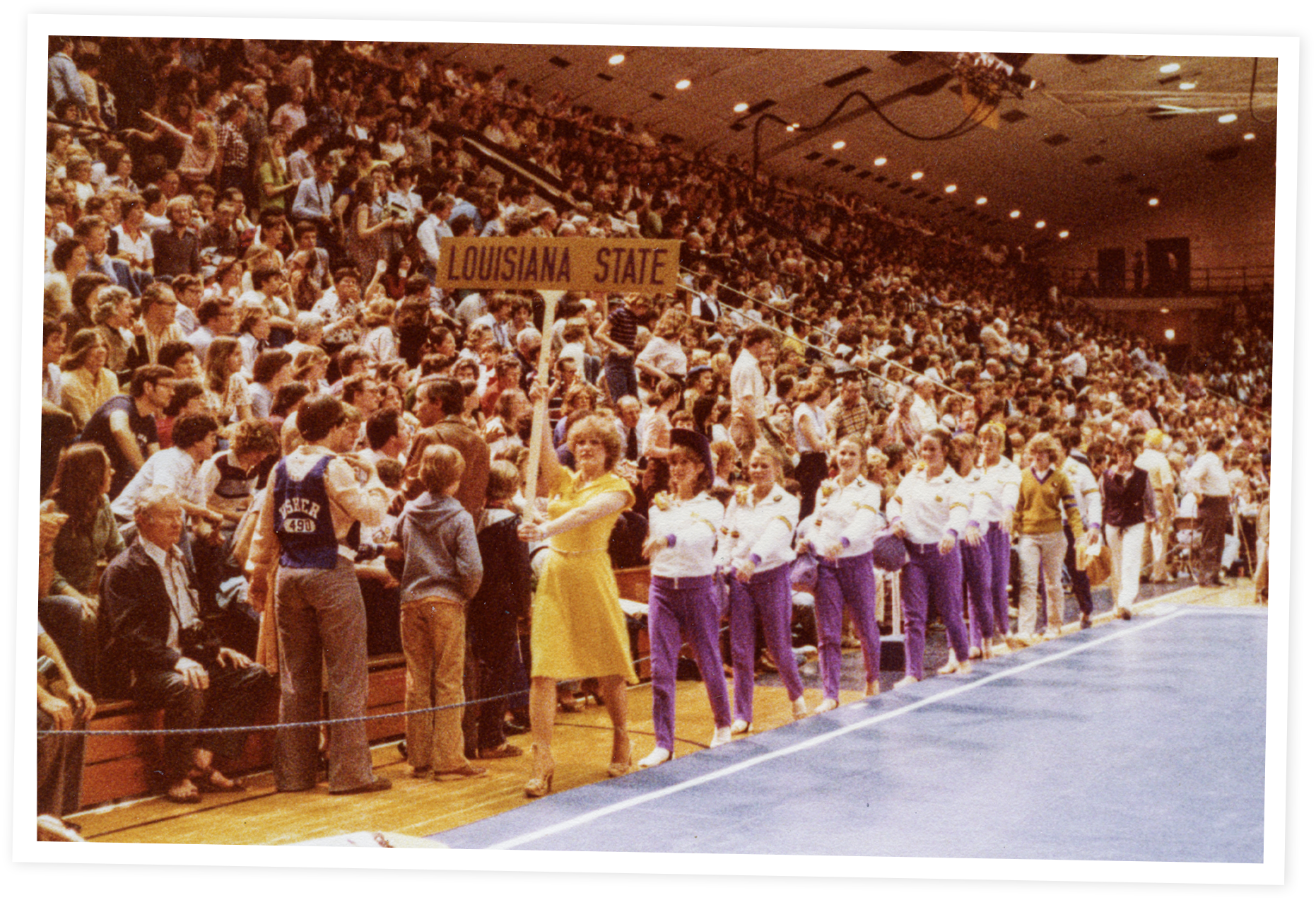 A large indoor gymnasium filled with a crowd of spectators.